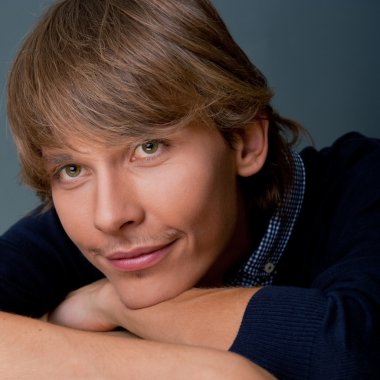 Portrait of young man leaning on box against grey wall. He is st clipart