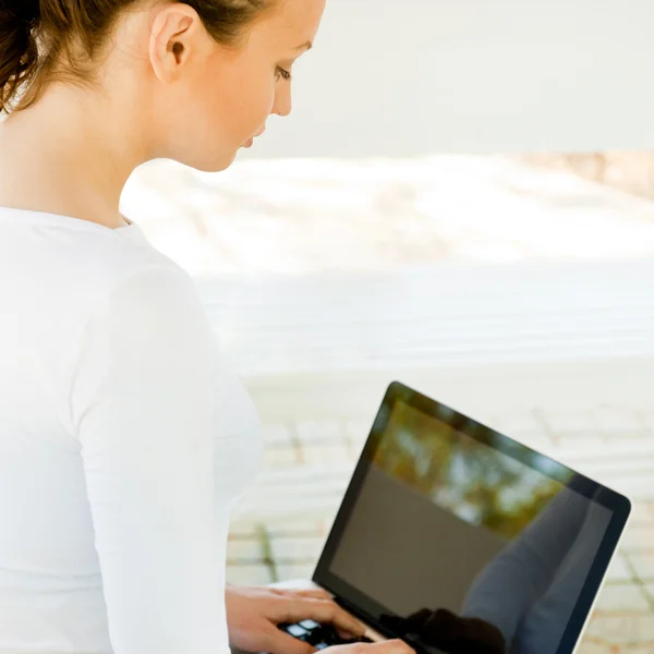 Femme d'affaires assise sur un banc travaillant sur un ordinateur portable dans le parc portant — Photo