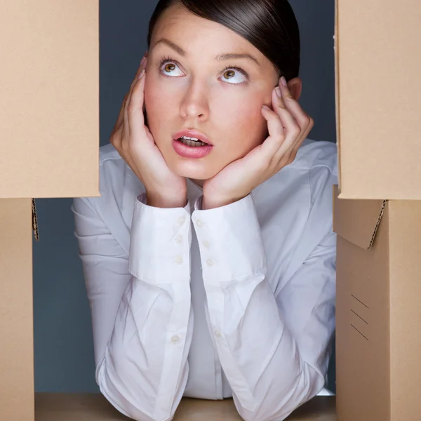 Portrait of young woman surrounded by lots of boxes. Lots of wor — Stock Photo, Image