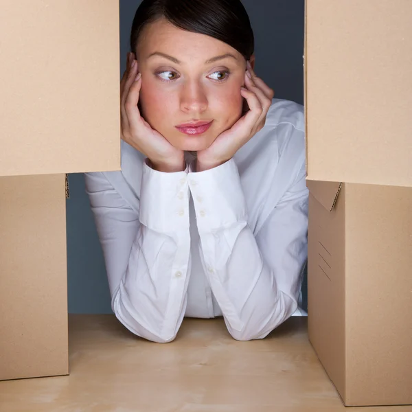 Πορτρέτο της νεαρής γυναίκας που περιβάλλεται από πολλά κουτιά. πολλή wor — Φωτογραφία Αρχείου