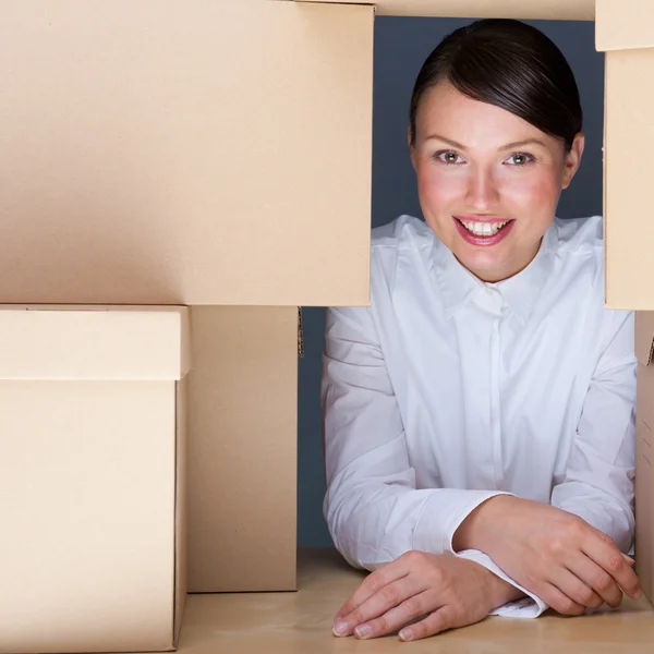 Portrait of young woman surrounded by lots of boxes. Lots of wor — Stock Photo, Image