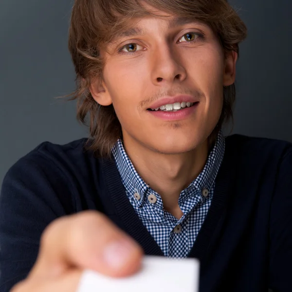 Homem de negócios entregando um cartão de visita em branco sobre fundo cinza — Fotografia de Stock