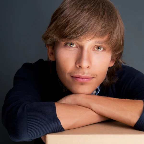Portrét mladého muže drží na box šedé zdi. On je st — Stock fotografie
