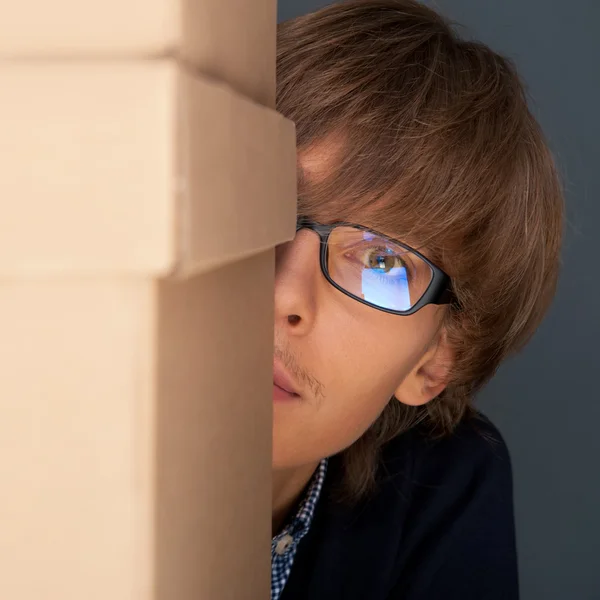 Portrait of young man holding on box against grey wall. He is st — Stock Photo, Image