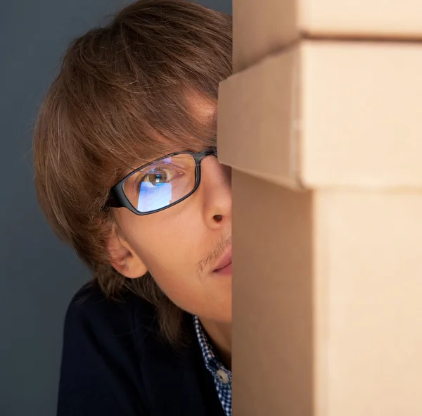 Retrato de un joven sosteniéndose en una caja contra una pared gris. Él es st —  Fotos de Stock