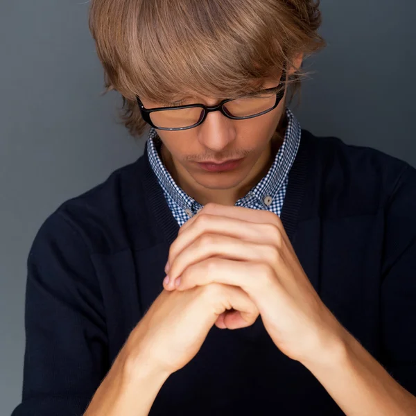 Młody człowiek modli się na szarym tle — Zdjęcie stockowe