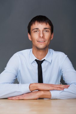 Portrait of young business man on a desk. He is sitting at his n clipart