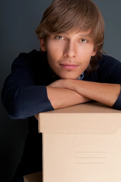Kutusu gri duvarın üzerinde tutan genç adam portresi. st olduğunu — Stok fotoğraf