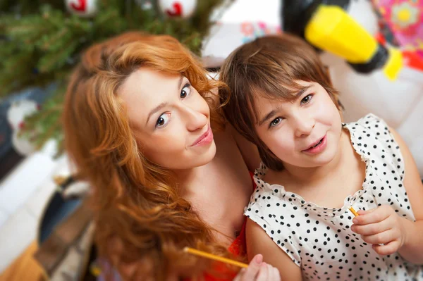 Mother and her daughter sitting together near christmas tree — Stock Photo, Image