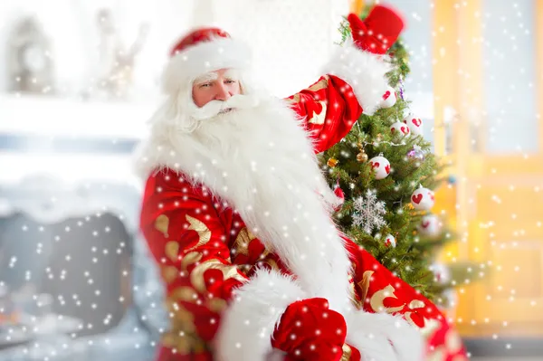 Santa κάθεται σε το χριστουγεννιάτικο δέντρο, κοντά στο τζάκι και ψάχνει — Φωτογραφία Αρχείου