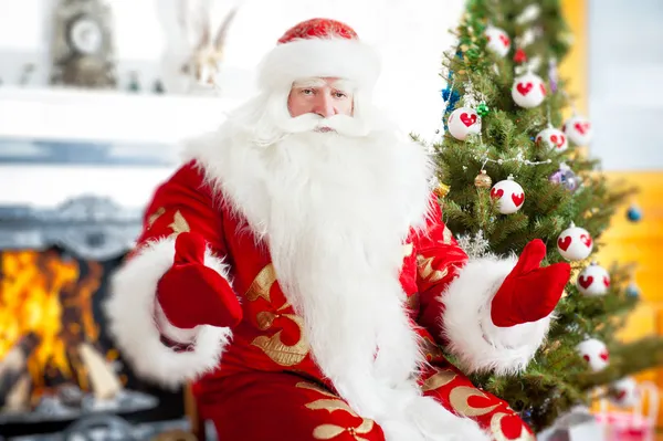 Santa κάθεται σε το χριστουγεννιάτικο δέντρο, κοντά στο τζάκι και ψάχνει — Φωτογραφία Αρχείου