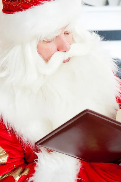 Santa sentado en el árbol de Navidad, cerca de la chimenea y la lectura —  Fotos de Stock