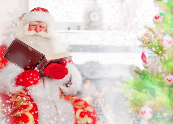 Noel Baba, yılbaşı ağacı, şömine ve okuma yakınında oturmak — Stok fotoğraf