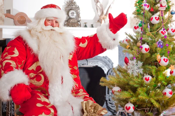 Santa sentado en el árbol de Navidad, cerca de la chimenea y mirando —  Fotos de Stock