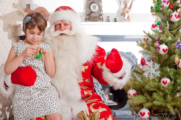 Weihnachtsthema: Weihnachtsmann und kleines Mädchen amüsieren sich. indoo — Stockfoto