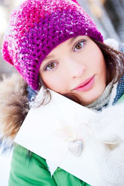 Happy young woman holding valentine card and looking at camera.