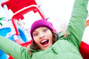 Portrait of young pretty playful woman riding down at playground