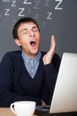 Bored businesspeople: man sitting at desk holding his head. Youn clipart