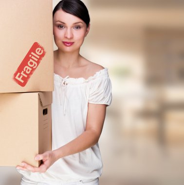 Closeup portrait of a young woman with boxes moving to her new home clipart
