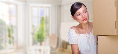 Smiling woman at her home holding boxes. She is Moving at her ne clipart