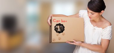 Portrait of young woman holding box with cat inside it clipart