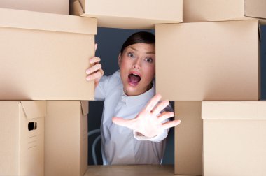Portrait of young woman surrounded by lots of boxes. Lots of wor clipart