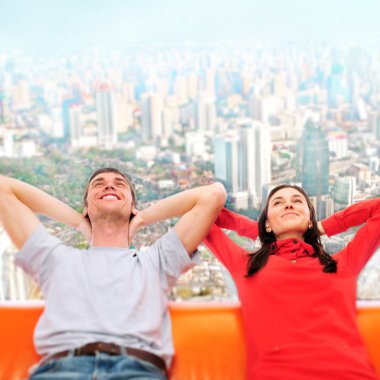 Closeup portrait of adult couple sitting on their sofa against b clipart