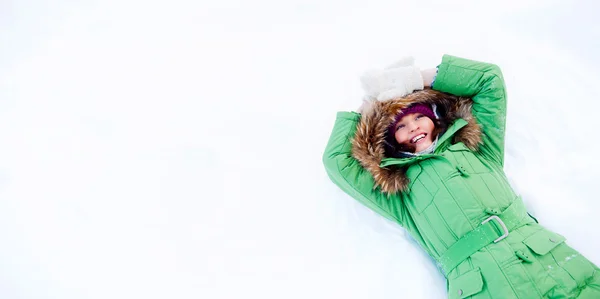 年轻女子在冬天躺在雪地上，仰望着天空 — 图库照片