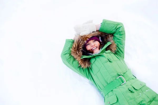Young woman lying on the snow in winter and looking to the sky — Stock Photo, Image