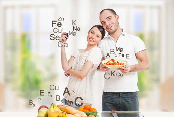 Jovem casal brincalhão em sua cozinha preparando comida saudável e — Fotografia de Stock