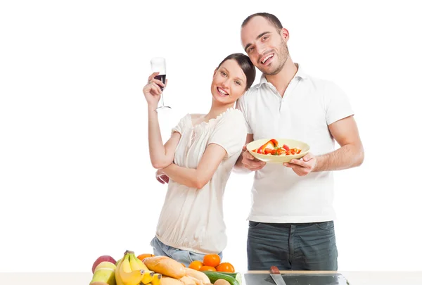 Jeune beau couple cuisinant une alimentation équilibrée sur un fond blanc — Photo