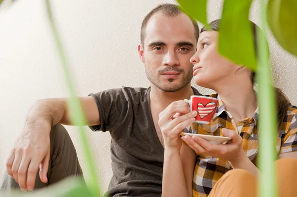Attractive young adult couple sitting close on hardwood floor in — Stock Photo, Image