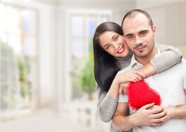Retrato de jovem casal com coração vermelho em pé em sua casa um — Fotografia de Stock