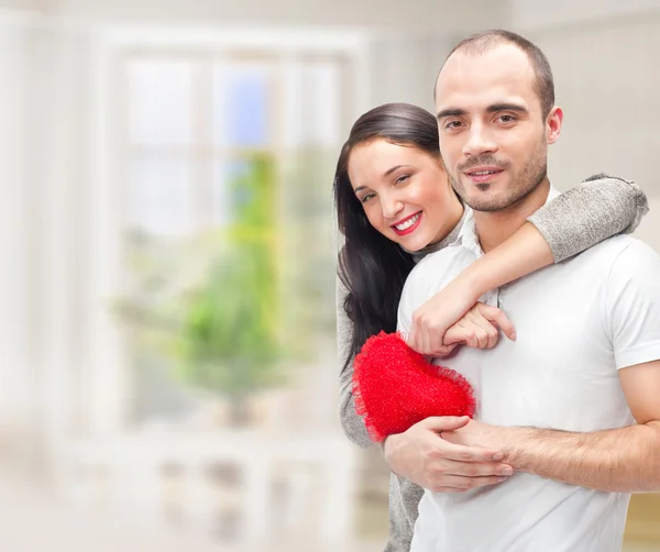 Retrato de jovem casal com coração vermelho em pé em sua casa um — Fotografia de Stock