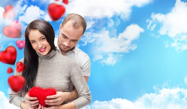 Glückliches junges erwachsenes Paar mit rotem Herz auf romantischem Hintergrund — Stockfoto