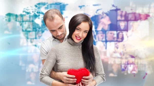 Portrait of young couple embracing and holding red heart. Standi — Stock Photo, Image