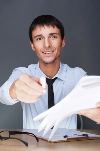 Handsome business man giving us to sign documents with pen — Stock Photo, Image