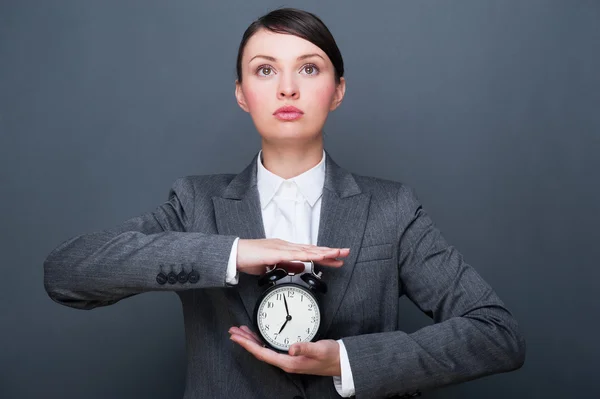 Imagen brillante de la mujer sosteniendo el reloj despertador contra el backgro gris —  Fotos de Stock
