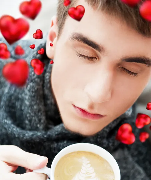 Porträtt av en ung man som dricker kaffe medan du sitter på armchai — Stockfoto