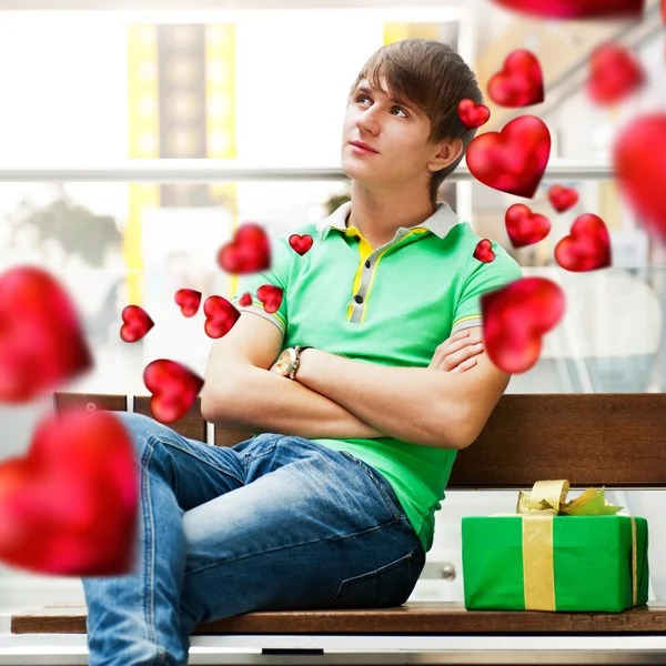Jeune homme à l'intérieur d'un centre commercial avec boîte cadeau attendant sa petite amie o — Photo