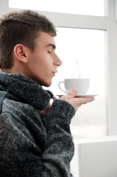 Portræt af en ung mand, der drikker kaffe med lukkede øjne - Stock-foto