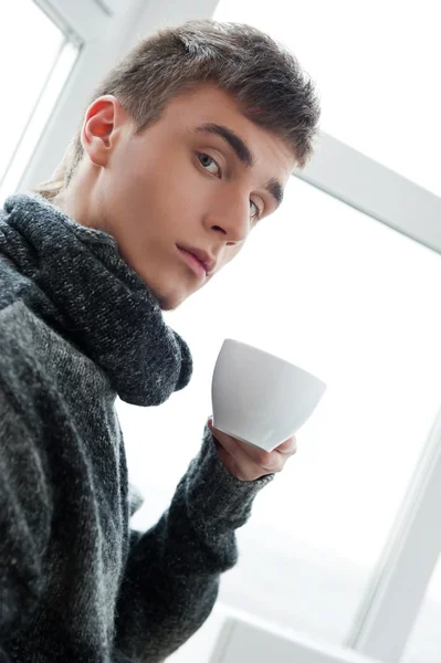コーヒーを飲みながらカメラを見て若い男の肖像 — ストック写真