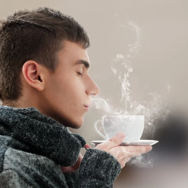 Nahaufnahme Porträt eines jungen Mannes, der zu Hause heiße Getränke genießt — Stockfoto