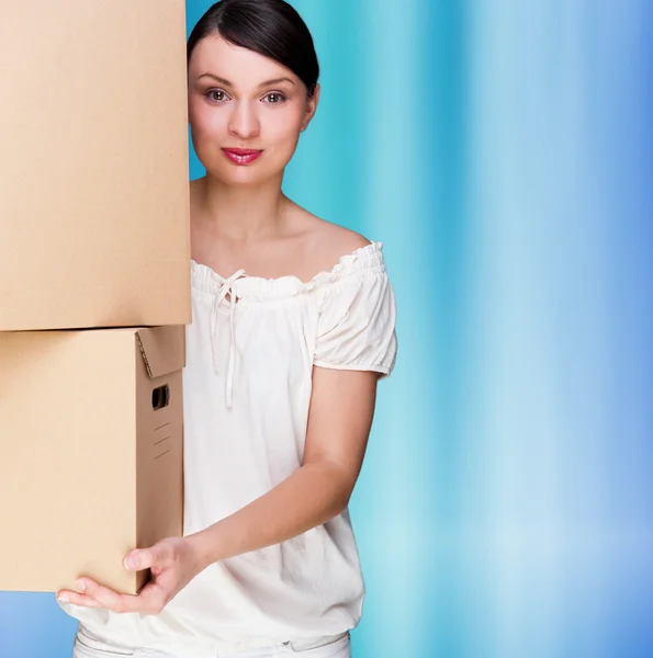 A nő, kezében egy doboz, kék háttérrel. Üres másolat tér — Stock Fotó
