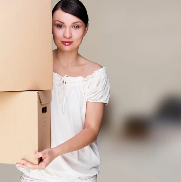 Smiling woman holding boxes after moving looking at the camera — Stock Photo, Image