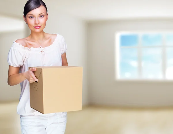 Усміхнена жінка вдома тримає коробки. Вона рухається до неї — стокове фото