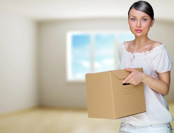 Mujer sonriente en su casa sosteniendo cajas. Ella se está moviendo en su ne — Foto de Stock