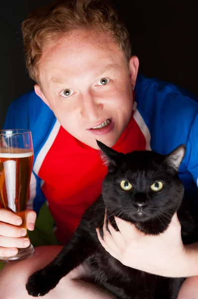 Retrato de um jovem segurando um copo de cerveja e uma grande ca preta — Fotografia de Stock