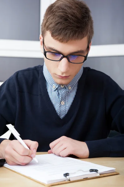 Gymnasiet - ung manlig student skriva anteckningar i klassrummet — Stockfoto