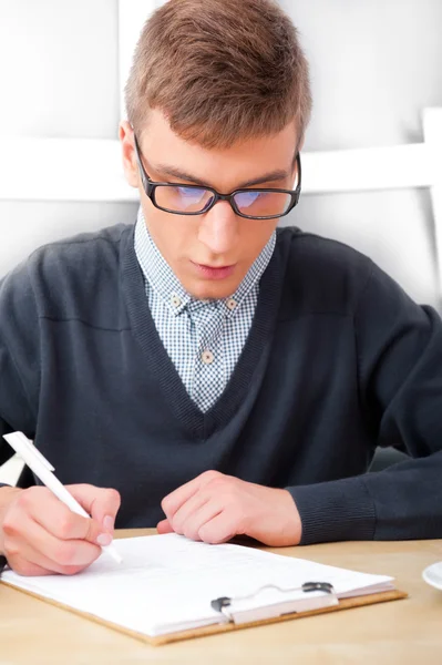 Gymnasiet - ung manlig student skriva anteckningar i klassrummet — Stockfoto